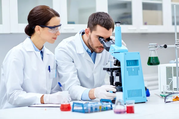 Jóvenes científicos haciendo pruebas o investigaciones en laboratorio — Foto de Stock