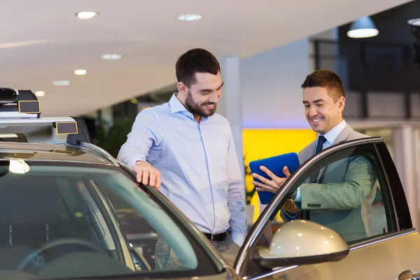 Šťastný muž s prodejci aut v autosalonu nebo salónek — Stock fotografie