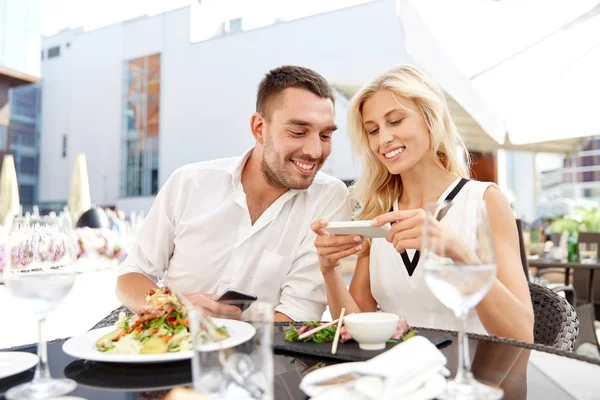 Pareja feliz con smatphone en la terraza del restaurante —  Fotos de Stock