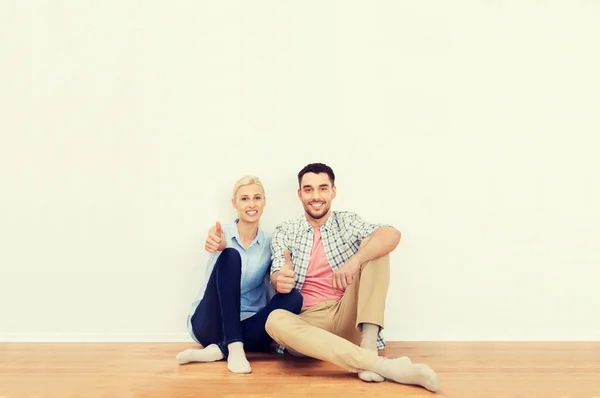 Lyckliga par visar tummen upp på nya hem — Stockfoto