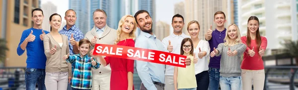 Personas felices con signo de venta que muestra los pulgares hacia arriba — Foto de Stock
