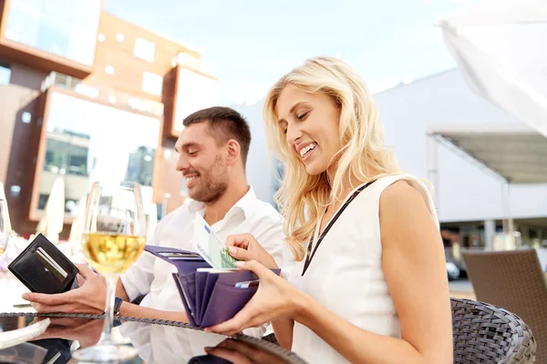 Feliz pareja con billetera pagando la factura en el restaurante —  Fotos de Stock