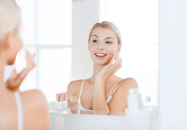 Gelukkige vrouw room toe te passen gezicht op de badkamer — Stockfoto