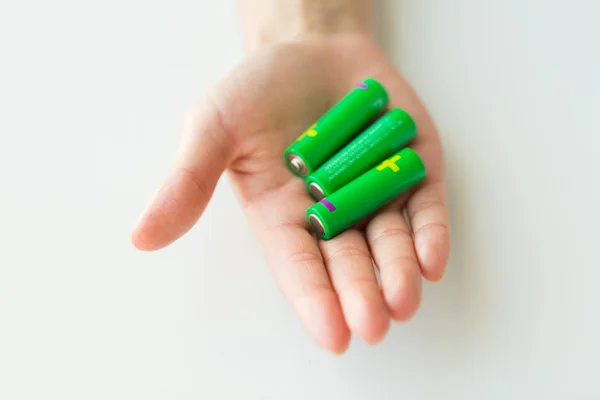 Close up of hand holding green alkaline batteries — Stock Photo, Image