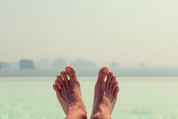 Close-up de pés masculinos sobre o mar e o céu na praia — Fotografia de Stock