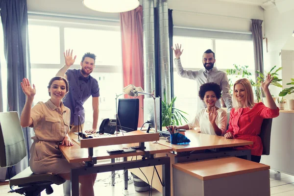 Щаслива творча команда махає руками в офісі — стокове фото