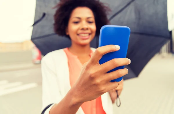 Närbild på kvinna med paraply och smartphone — Stockfoto