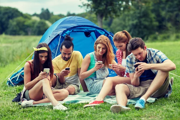Amici con smartphone e tenda in campeggio — Foto Stock