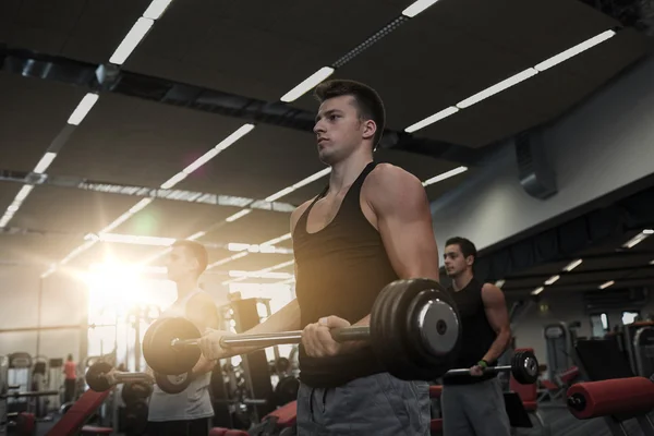 Group of men flexing muscles with barbell in gym — Stock Photo, Image