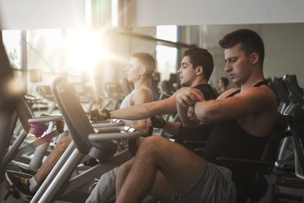 Men working out on exercise bike in gym — Stock Photo, Image