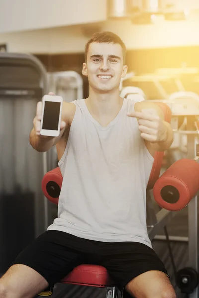 Jovem sorridente com smartphone no ginásio — Fotografia de Stock