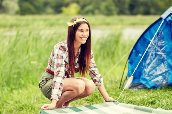 Glückliche junge Frau legt Decke auf Zeltplatz Stockfoto