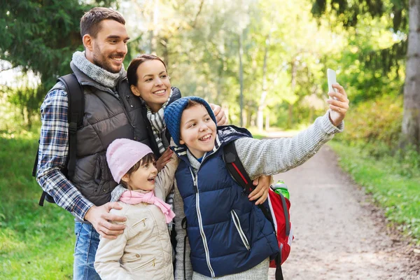 Семья с рюкзаками делает селфи со смартфона — стоковое фото