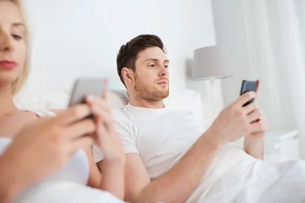 Couple avec smartphones au lit — Photo