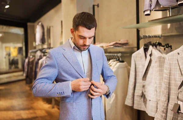 Gelukkig jonge man probeert jas op in kledingwinkel — Stockfoto