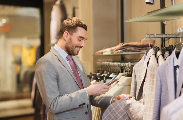 Man in pak met smartphone bij kledingwinkel — Stockfoto