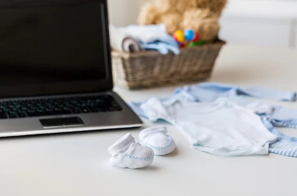 Fermer les vêtements pour bébés, jouets et ordinateur portable à la maison — Photo