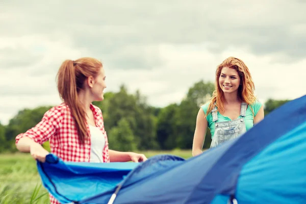 Улыбающиеся друзья, устанавливающие палатку на открытом воздухе — стоковое фото