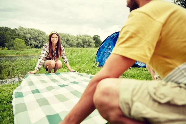 Happy couple laying picnic blanket at campsite — Stock Photo, Image