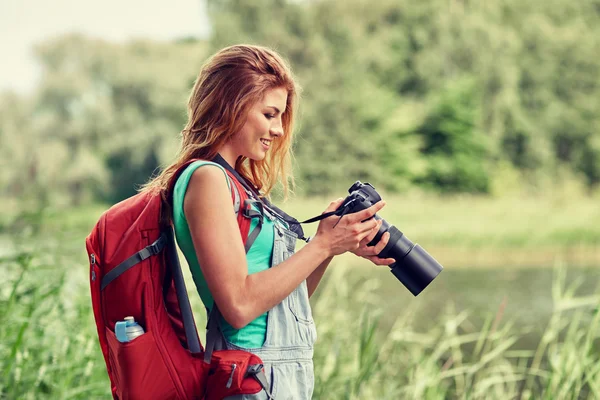 Mulher feliz com mochila e câmera ao ar livre — Fotografia de Stock