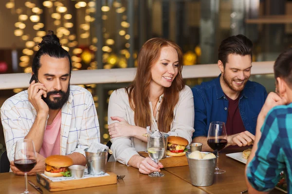 Muž s smartphone a přáteli v restauraci — Stock fotografie