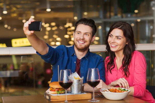 Пара делает селфи на смартфоне в ресторане — стоковое фото