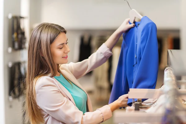 Gelukkig jonge vrouw kleding in winkelcentrum kiezen — Stockfoto