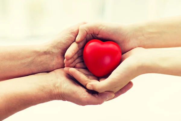 Senior en jonge vrouw handen met rood hart — Stockfoto