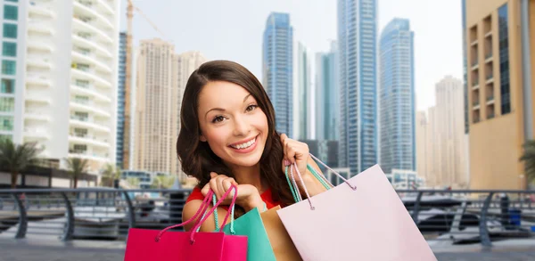 Счастливая женщина с сумками для покупок над городом Дубай — стоковое фото