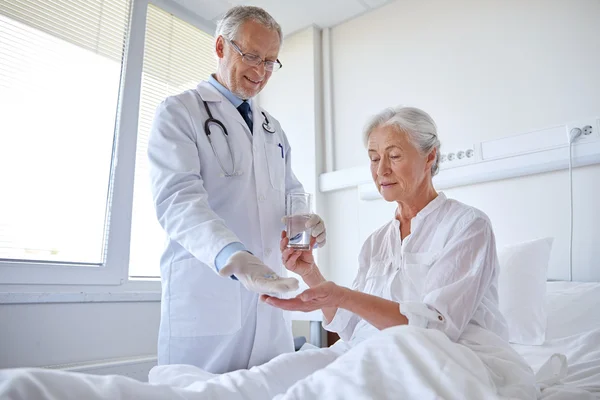 Doctor giving medicine to senior woman at hospital — Stock Photo, Image