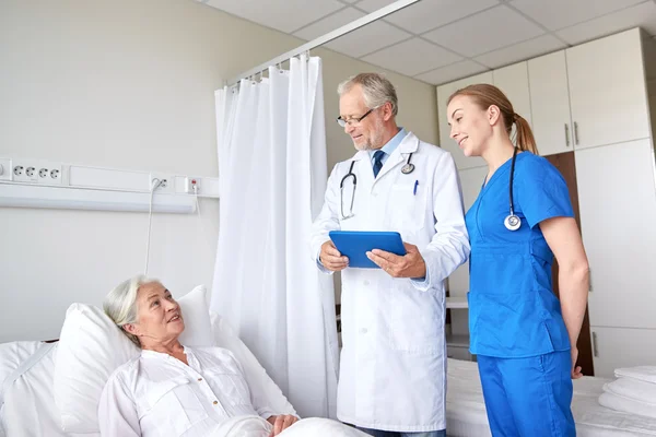 Médico y enfermera visitando a una mujer mayor en el hospital — Foto de Stock