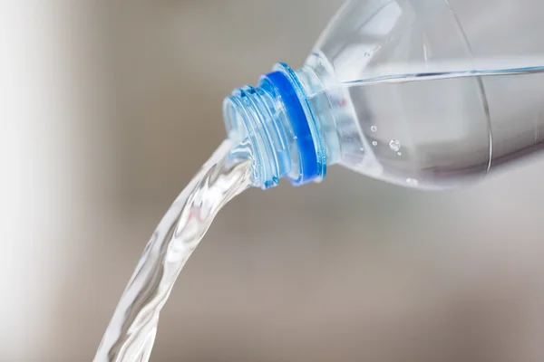 Primo piano dell'acqua versata dalla bottiglia di plastica — Foto Stock