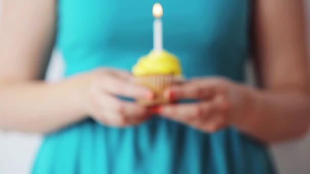 Mujer con vela encendida en cupcake de cumpleaños — Vídeos de Stock