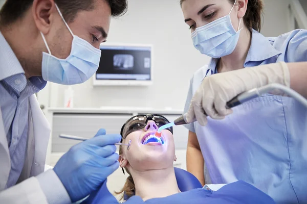 Dentists treating woman patient teeth at clinic — ストック写真