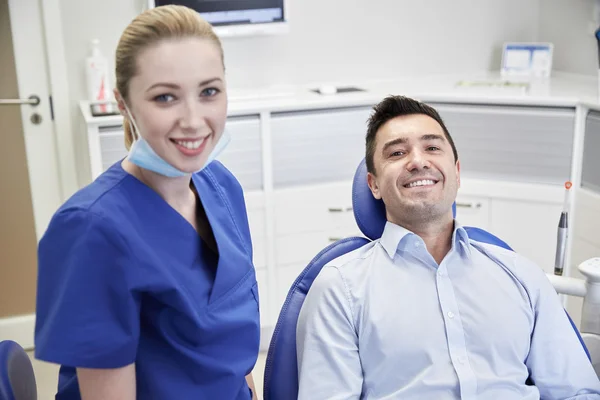 Gelukkig vrouwelijke tandarts met man patiënt bij kliniek — Stockfoto