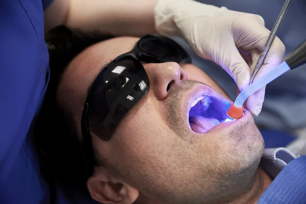 Gros plan du patient masculin avec lumière de durcissement dentaire — Photo