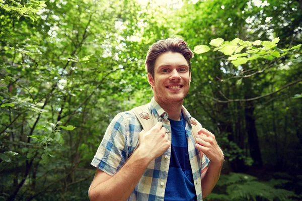 Jovem sorridente com mochila caminhadas na floresta — Fotografia de Stock