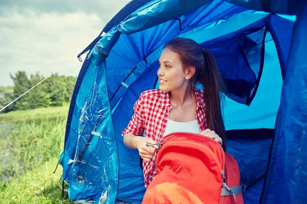 Feliz jovem mulher sentada na tenda no acampamento — Fotografia de Stock