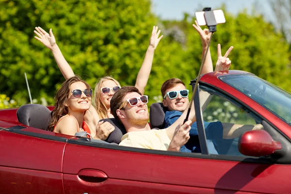 Amigos dirigindo em carro cabriolet e tomar selfie — Fotografia de Stock