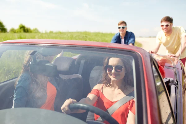 Happy friends pushing broken cabriolet car — Stock Photo, Image