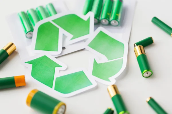 Close up of batteries and green recycling symbol — Stock Photo, Image