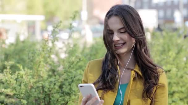 Šťastná mladá žena s smartphone a sluchátka — Stock video