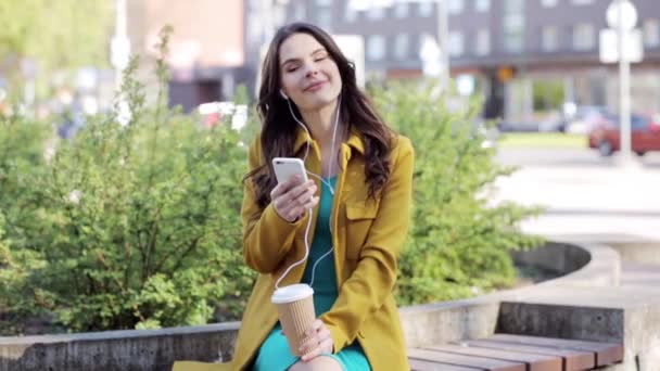 Счастливая молодая женщина со смартфоном и наушниками — стоковое видео