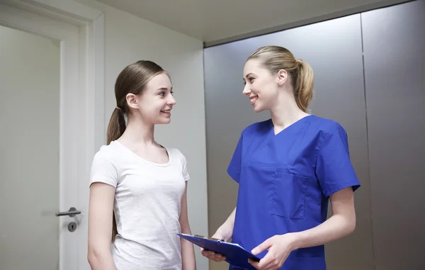 Улыбающаяся медсестра с планшетом и девушка в больнице — стоковое фото