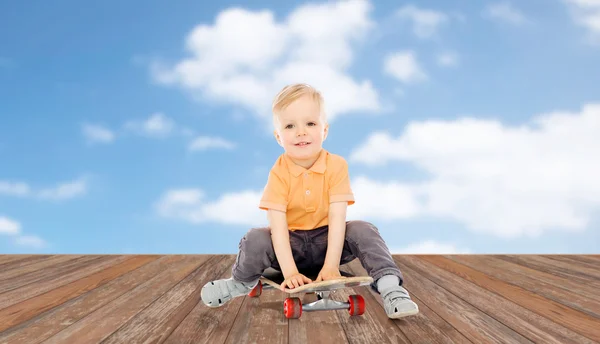 Bambino felice seduto sullo skateboard — Foto Stock