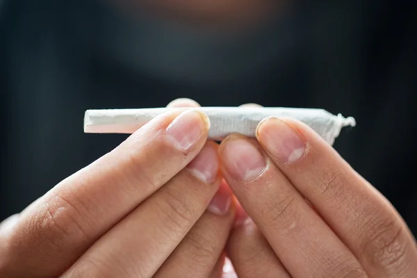 Perto de mãos viciadas com maconha conjunta — Fotografia de Stock