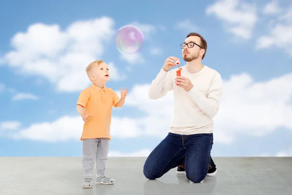 Vader en zoon blazen van zeepbellen en plezier — Stockfoto