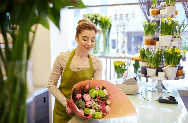 Sonriente florista mujer embalaje ramo en floristería — Foto de Stock