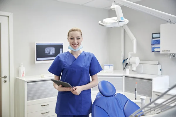 Dentista feminino feliz com tablet pc na clínica — Fotografia de Stock