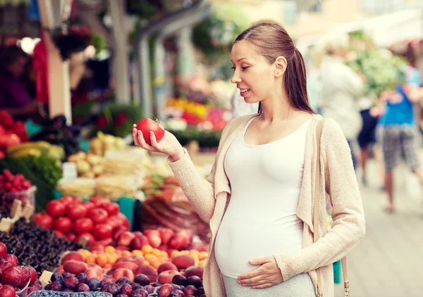 Беременная женщина выбирает еду на рынке — стоковое фото